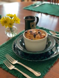Bread Pudding in white ramakin on green plate with utentensil