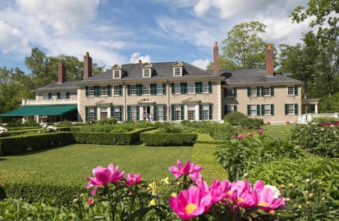 Exterior rear of large two-story house with a green awning and well-maintained garden.