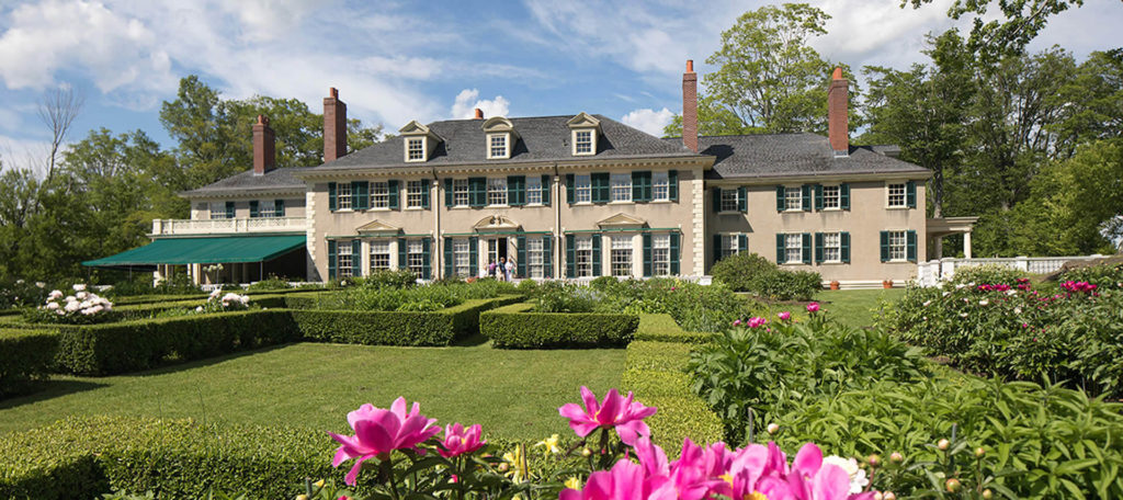 Exterior rear of large two-story house with a green awning and well-maintained garden.