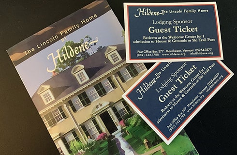 An information packet and two tickets to the Lincoln Family House, on a dark colored table.