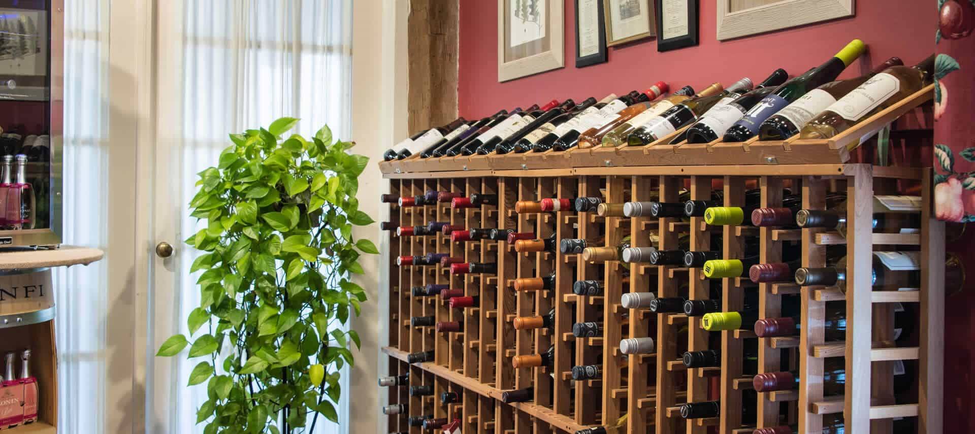 A large wooden wne rack filled with many bottles of wine sits next to a set of french doors. 